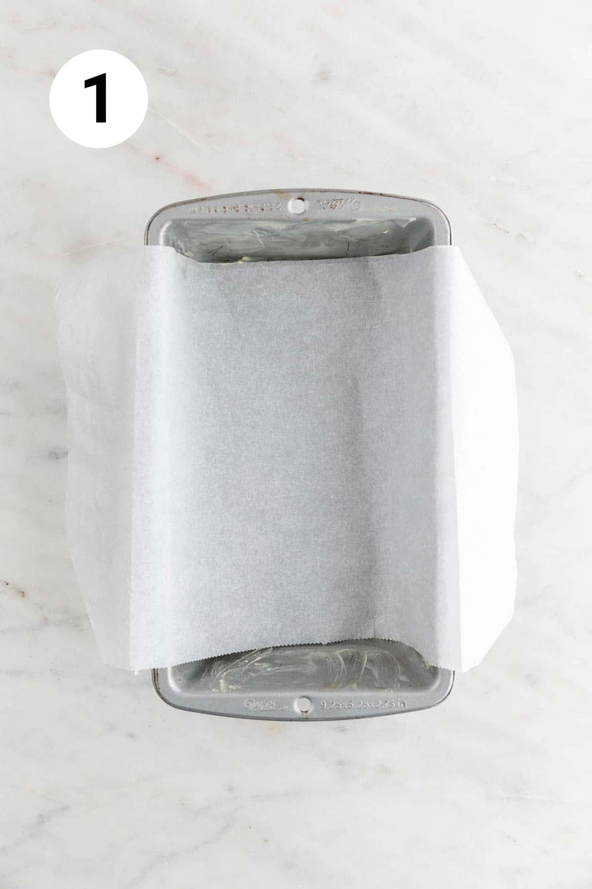 A loaf pan lined with parchment paper and greased with vegan butter.