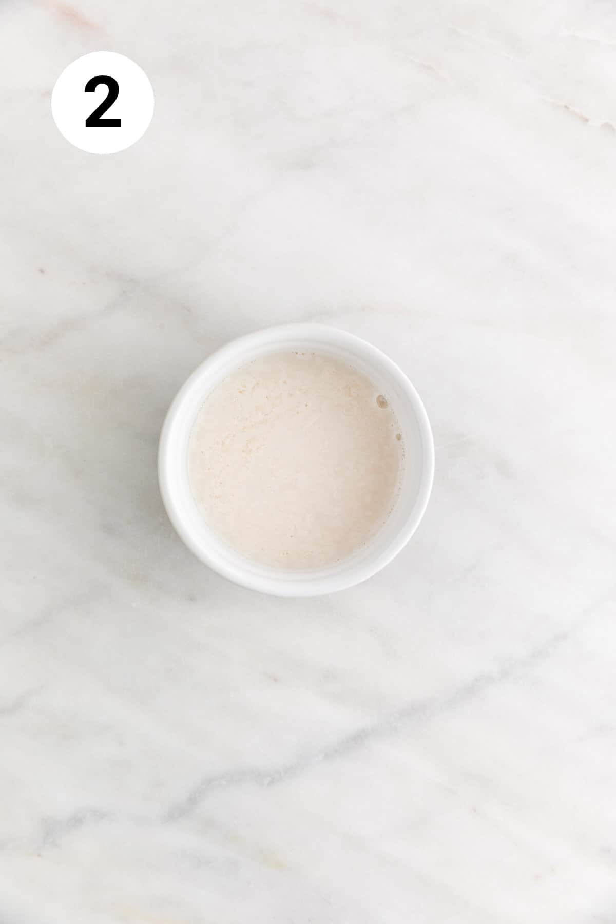 Mixture of non-dairy milk and apple cider vinegar in a small bowl.
