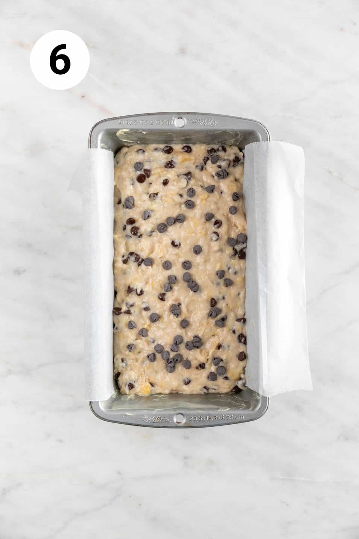 Vegan banana bread batter in the lined loaf pan after adding the chocolate chips.