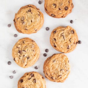Lots of vegan chocolate chip cookies on a marble slab.