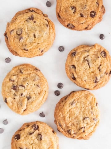 Lots of vegan chocolate chip cookies on a marble slab.