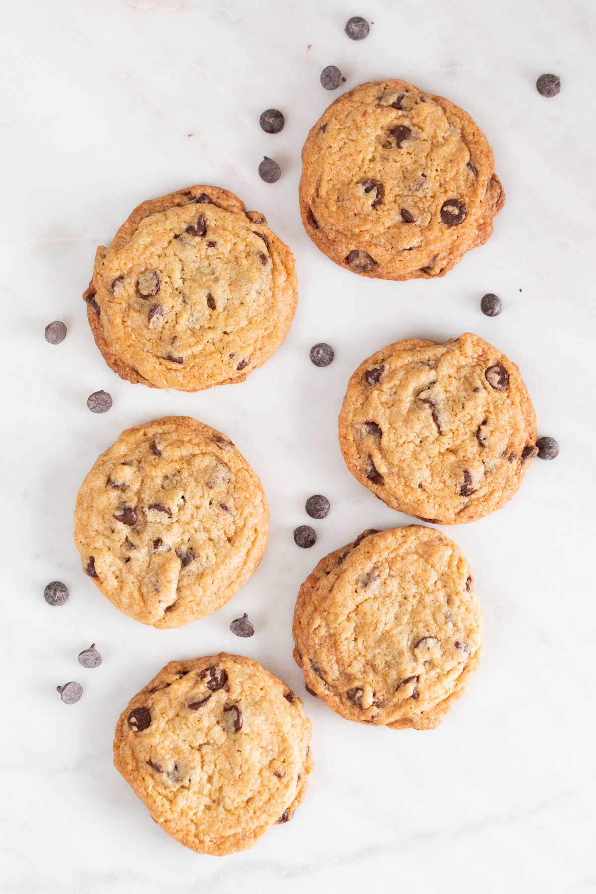 Lots of vegan chocolate chip cookies on a marble slab.