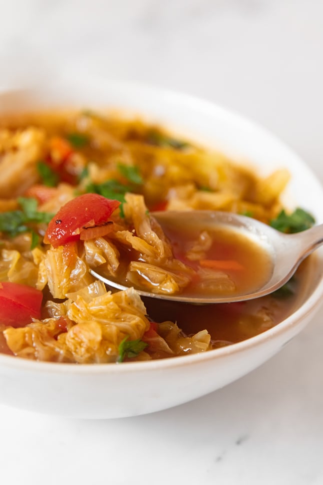 Close-up shot of a bowl of cabbage soup with a spoon