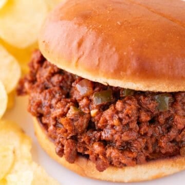 Vegan sloppy joes on white dish, accompanied by crispy potato chips.