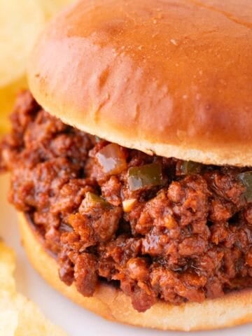 Vegan sloppy joes on white dish, accompanied by crispy potato chips.