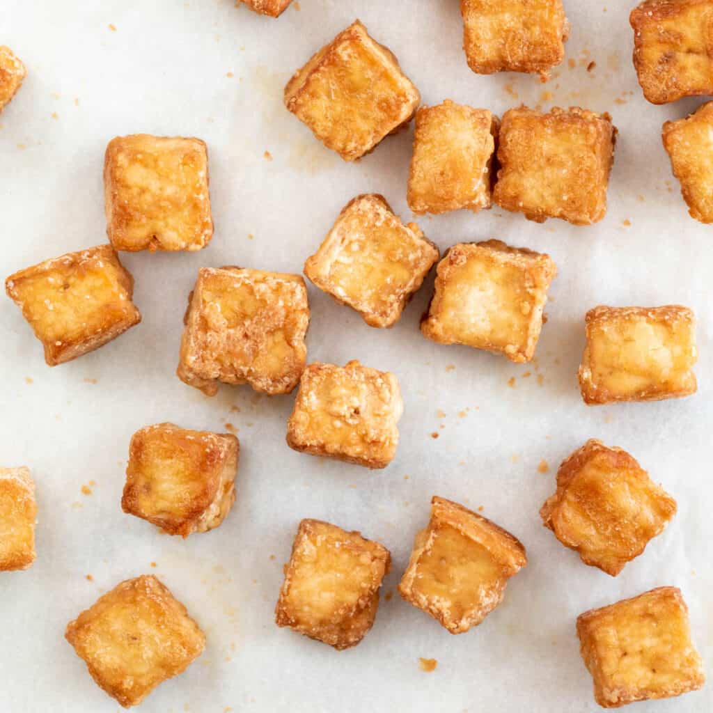 Overview of baked tofu cubes onto a lined baking sheet.