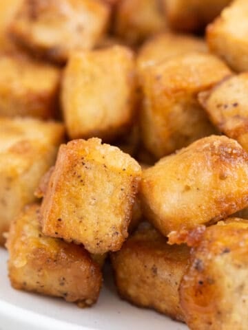 Square photo of a dish with crispy pan-fried tofu cubes.