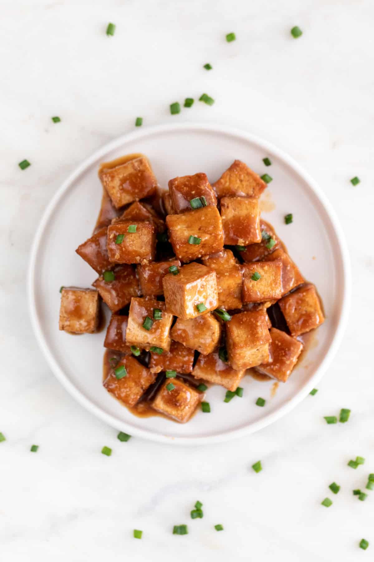 Overview of a dish with marinated tofu garnished with chopped chives.