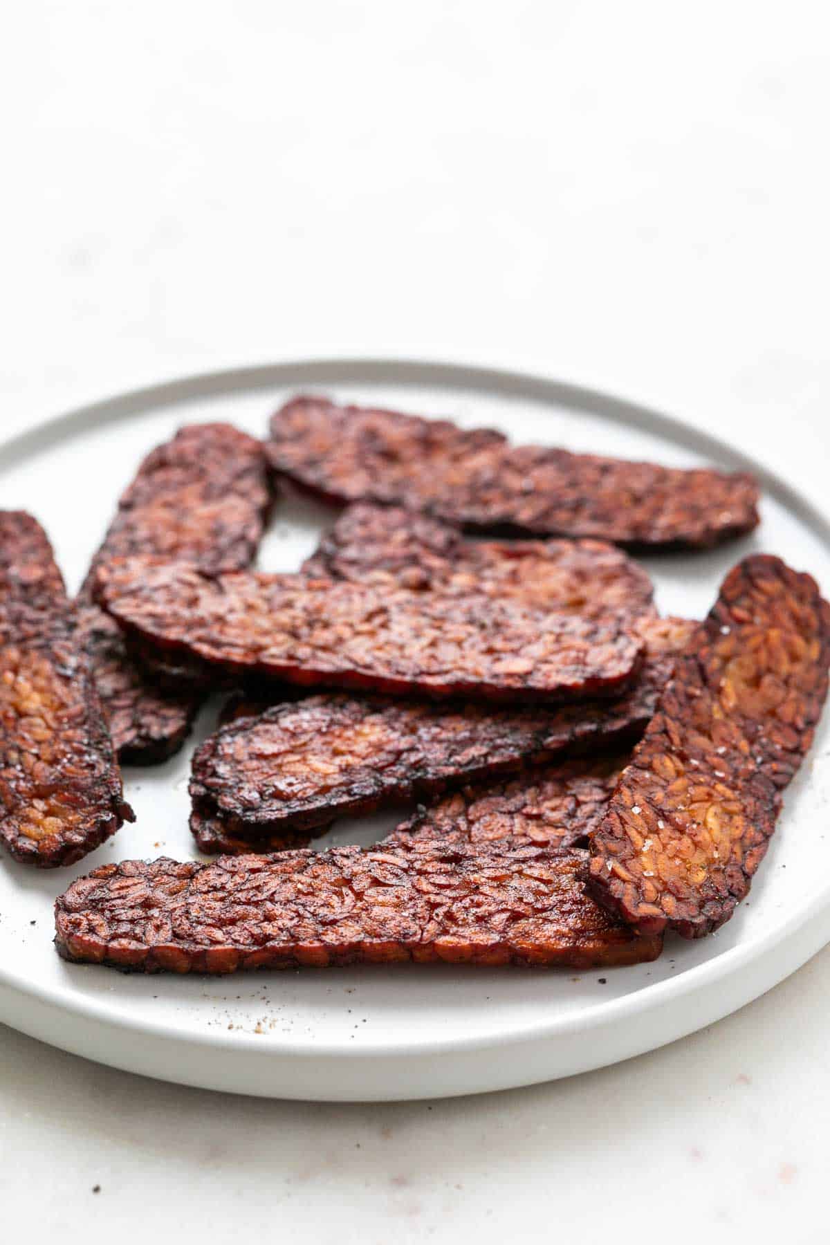 White plate with slices of tempeh bacon.