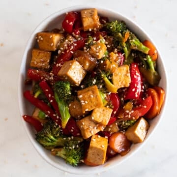 A bowl with tofu stir fry garnished with some sesame seeds.