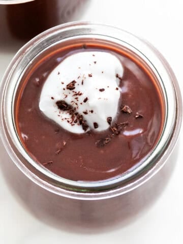 Vegan chocolate pudding in a glass, adorned with whipped cream and chocolate curls.
