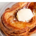 Overview of a stalk of vegan French toast on a plate with some maple syrup and vegan butter on top.