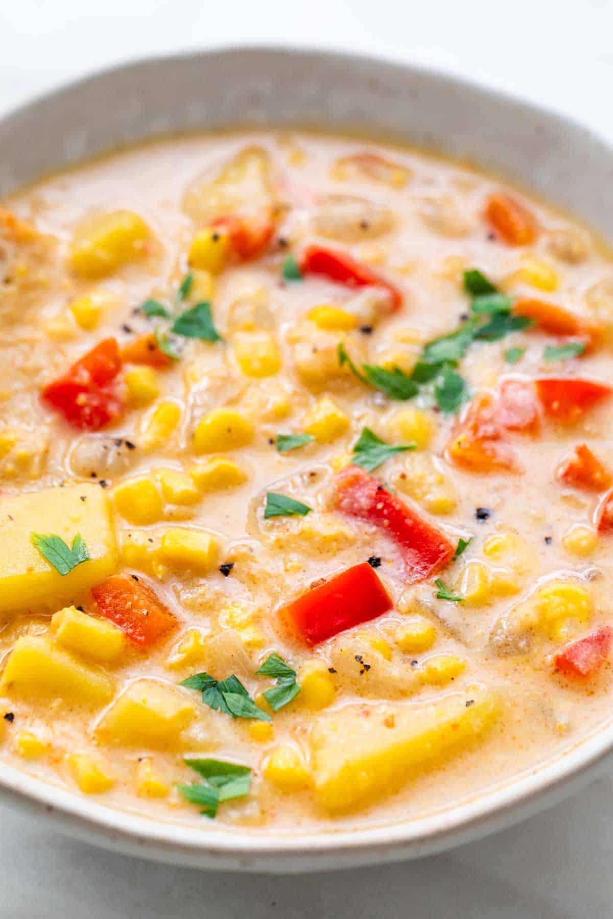Bowl of vegan potato and corn chowder topped with fresh parsley.