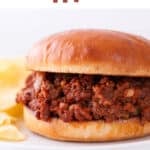 Vegan sloppy joe sandwich on a white plate with a side of potato chips.