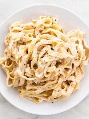 Vegan cashew alfredo pasta sprinkled with ground black pepper.