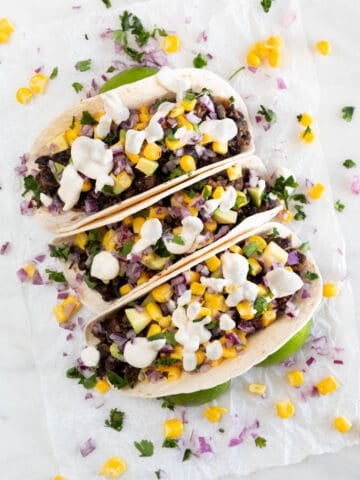 Three vegan tacos onto a white board.
