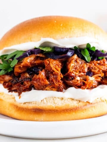 Vegan BBQ jackfruit pulled pork sandwich topped with vegan mayo and vegetables.