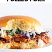 BBQ jackfruit pulled pork sandwich with vegan mayo, parsley, and red cabbage, with a bite taken.