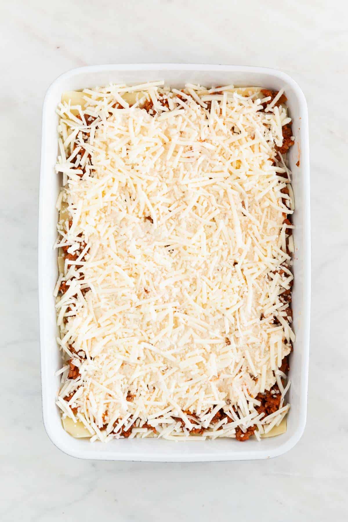 A casserolle dish with the second layer of vegan mozzarella.