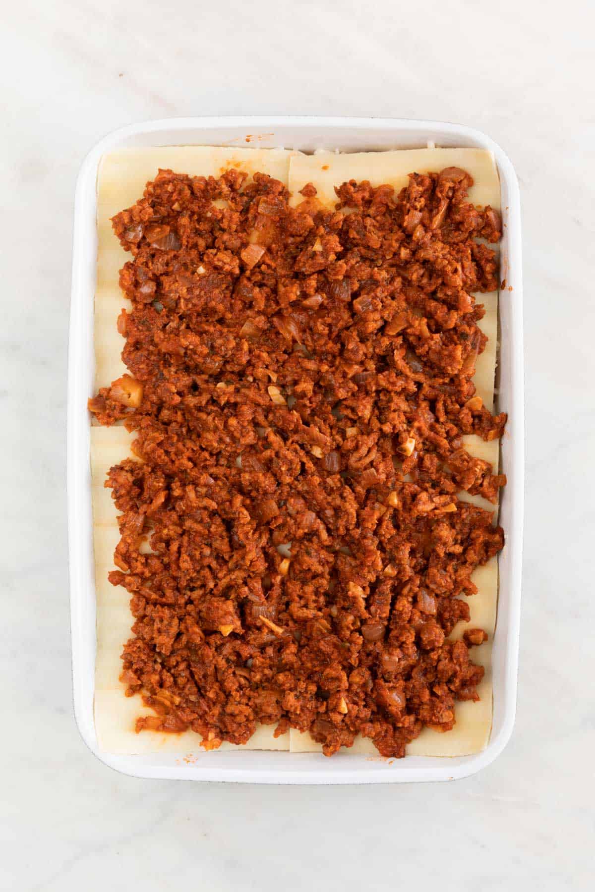 A casserole dish with the last 4 lasagna noodles and the remaining vegan meat sauce.