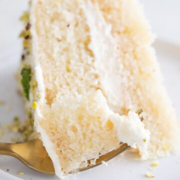 Close-up photo of a dish with a slice of vegan lemon cake and a fork