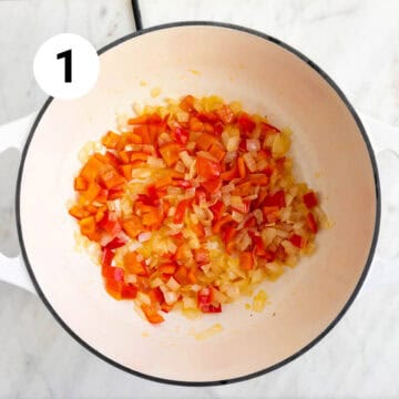 Garlic and red bell pepper sautéed in a large pot.