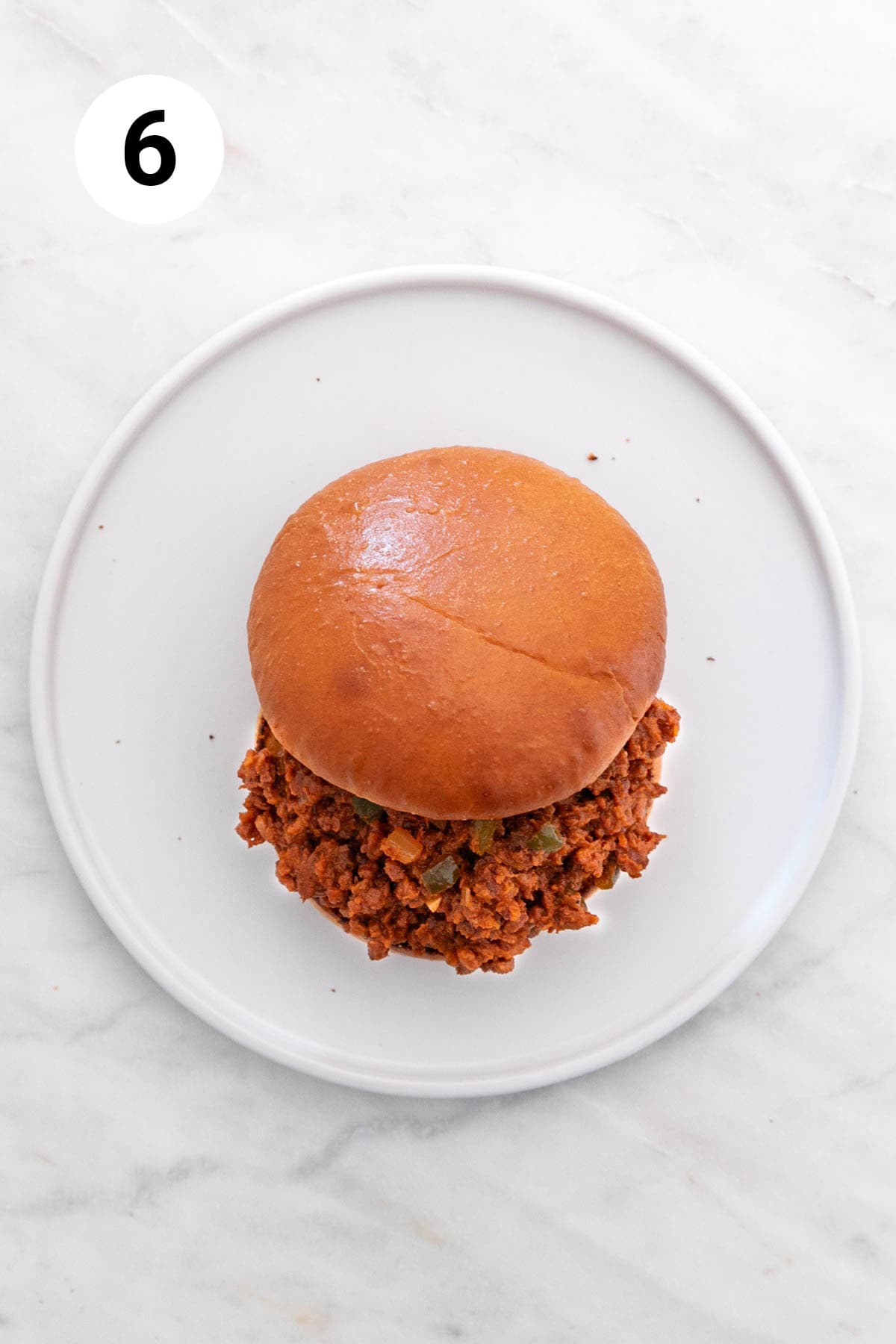 A vegan sloppy joe sandwich on a white dish.